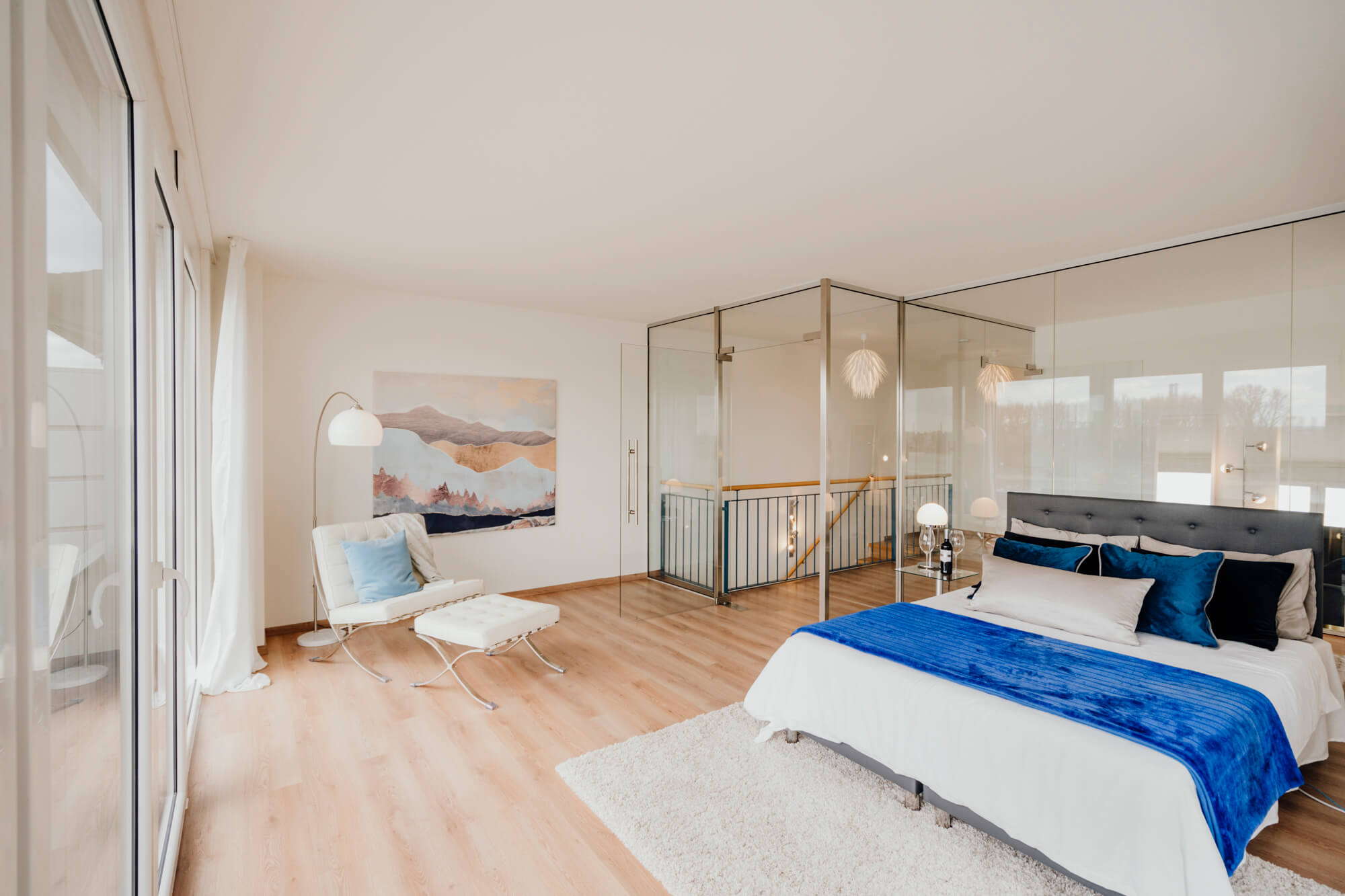 Lisa Treusch Fotografie Mainz Immobilien Fotografie Innenaufnahme Schlafzimmer in Blautönen dekoriert mit Blick auf Bett, Sessel und Treppenaufgang
