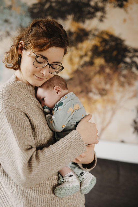 Mutter haelt Neugeborenes liebevoll im Arm bei Neugeborenen Shooting – Lisa Treusch Familienfotografin Mainz